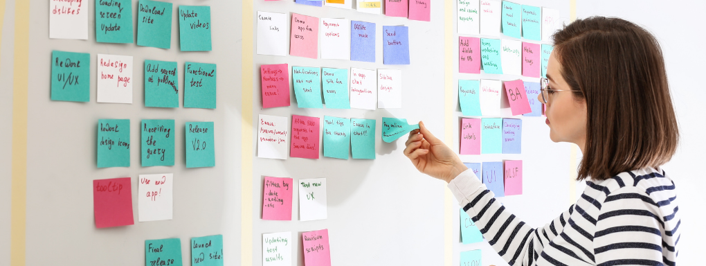 Woman removing sticky note from a wall as part of the scrum process