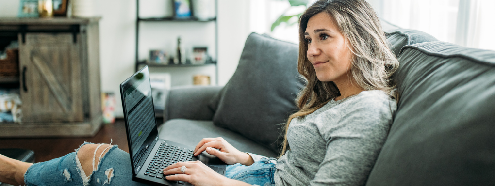 Woman working from home on sofa with laptop 