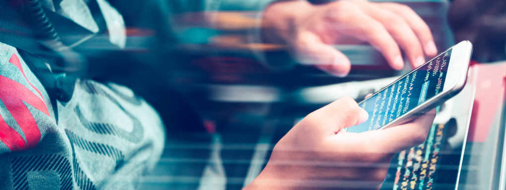 Cropped shot of a mans hands on a smartphone looking at computer code with a colour blur effect applied.