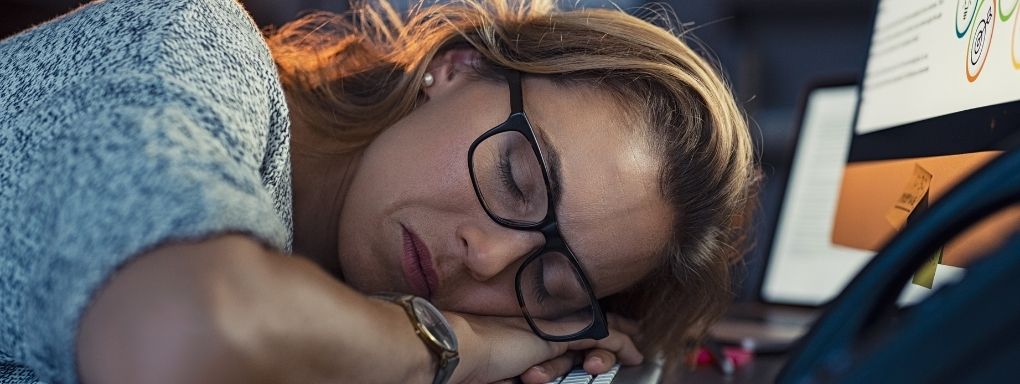 Woman asleep at office desk still wearing her glasses